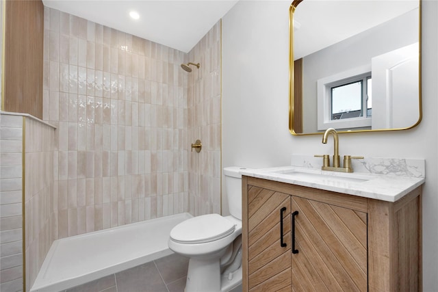 bathroom with toilet, tiled shower, tile patterned flooring, and vanity