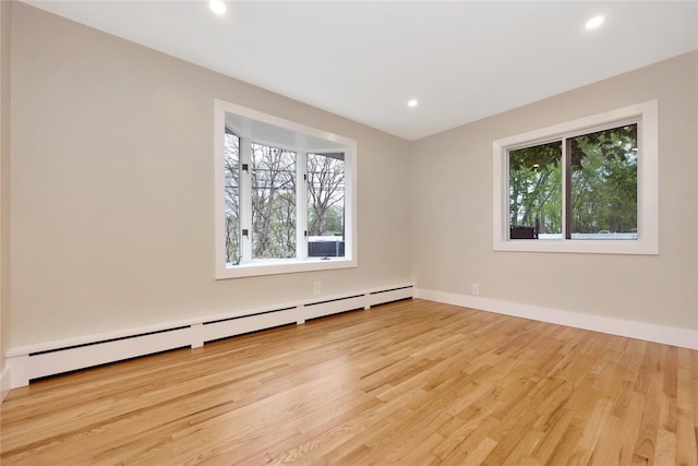 empty room with a baseboard radiator, wood finished floors, recessed lighting, and baseboards