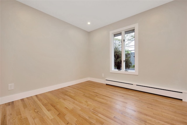 empty room with a baseboard radiator, baseboards, light wood-type flooring, and recessed lighting