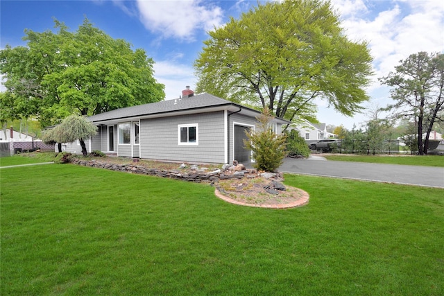 view of front facade featuring a garage, asphalt driveway, and a front lawn