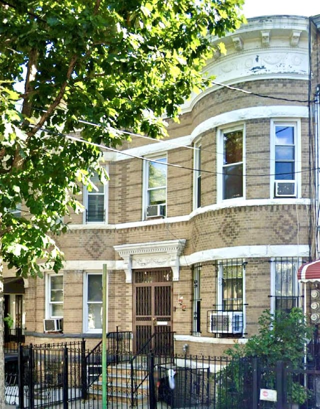 view of front facade with a fenced front yard, cooling unit, and brick siding
