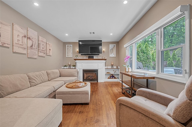 living area with wood finished floors, recessed lighting, a fireplace, and baseboards