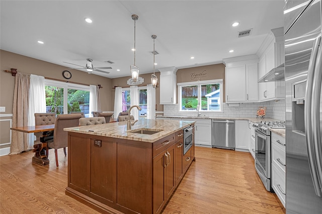 kitchen with built in appliances, a sink, plenty of natural light, an island with sink, and recessed lighting
