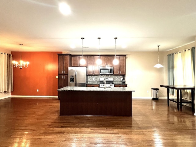 kitchen featuring appliances with stainless steel finishes, baseboards, tasteful backsplash, and an island with sink