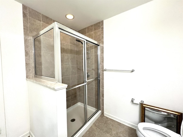bathroom with a stall shower, tile patterned flooring, toilet, and baseboards