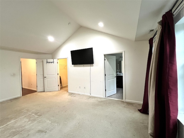 unfurnished bedroom with lofted ceiling, baseboards, ensuite bathroom, a spacious closet, and light carpet