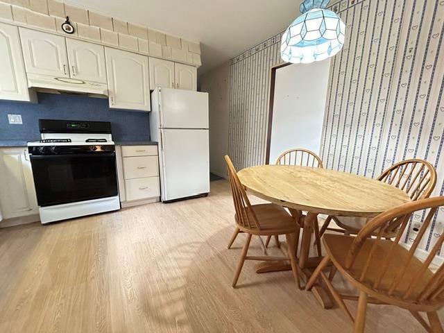kitchen featuring gas stove, freestanding refrigerator, under cabinet range hood, light wood-style flooring, and white cabinetry