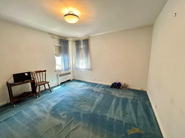 carpeted spare room with radiator heating unit and baseboards
