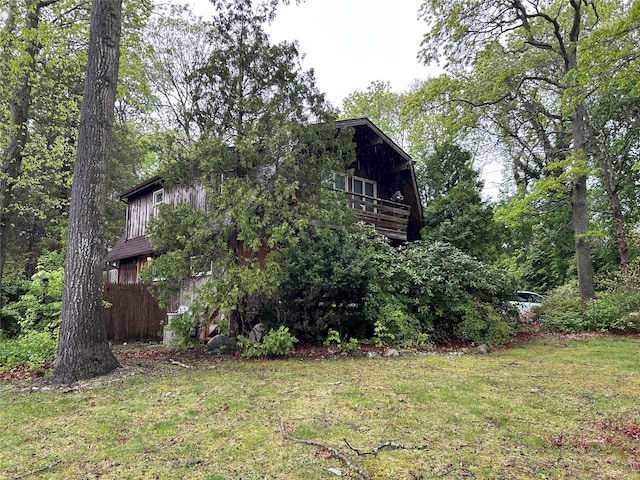 view of side of property with a yard and a balcony