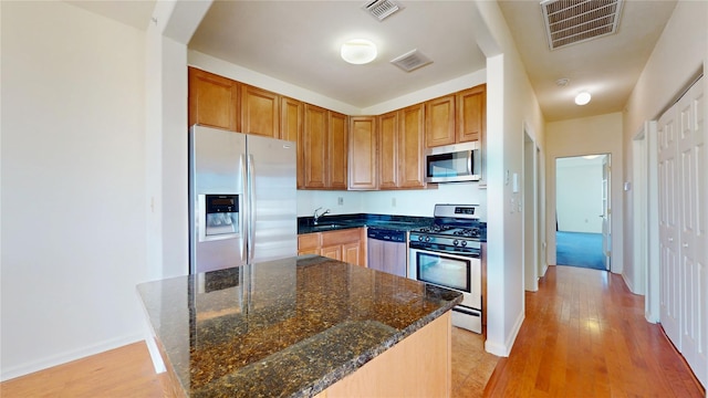 6910 Beach Front Rd, Arverne, NY 11692 - kitchen with appliances with stainless steel finishes, a sink, light wood-style flooring, baseboards, and dark stone countertops