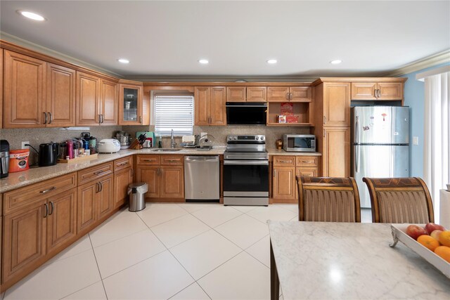 kitchen with brown cabinets, a sink, appliances with stainless steel finishes, tasteful backsplash, and ornamental molding