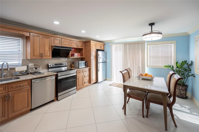 kitchen featuring a sink, stainless steel appliances, brown cabinetry, tasteful backsplash, and ornamental molding
