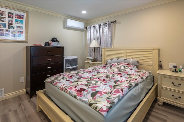 bedroom with a wall mounted air conditioner, wood finished floors, visible vents, recessed lighting, and crown molding