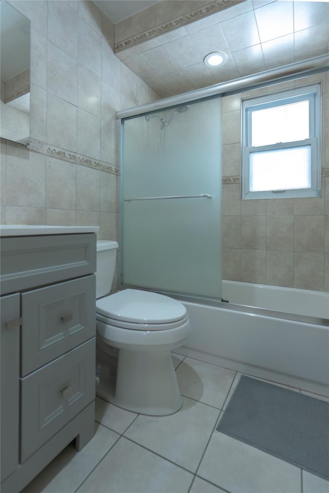 full bath featuring toilet, tile walls, vanity, tile patterned floors, and enclosed tub / shower combo