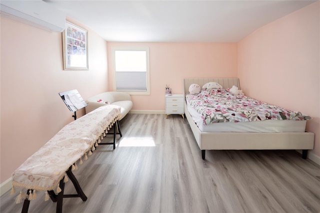 bedroom with baseboards, an AC wall unit, and wood finished floors