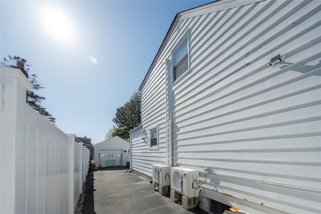view of property exterior featuring a detached garage, an outbuilding, fence, and ac unit