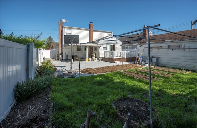 back of property featuring a fenced backyard, a patio area, a wooden deck, and a lawn