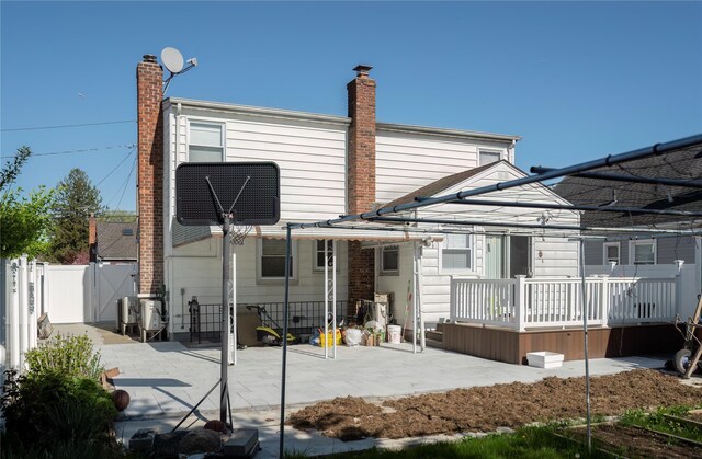 rear view of property featuring a patio area, a chimney, fence, and a deck
