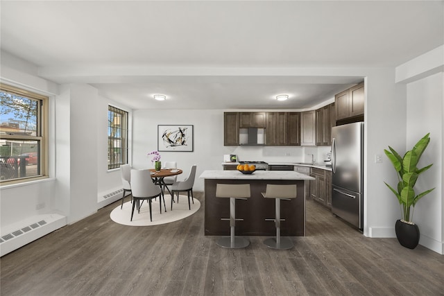 kitchen with a center island, a sink, freestanding refrigerator, dark brown cabinetry, and dark wood finished floors