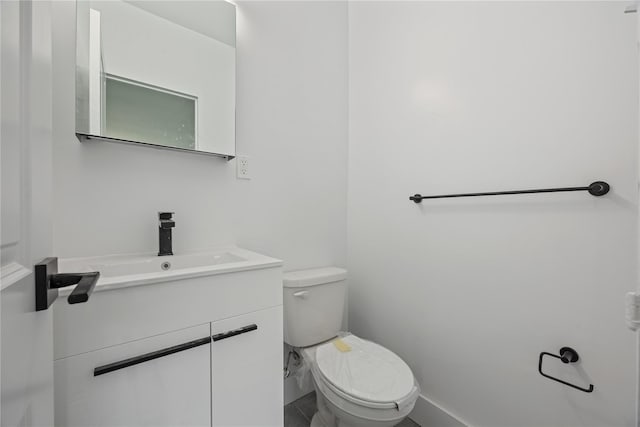 half bathroom with toilet, baseboards, and vanity