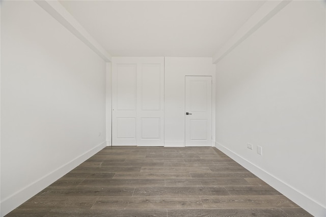 unfurnished bedroom with baseboards, a closet, and dark wood-type flooring
