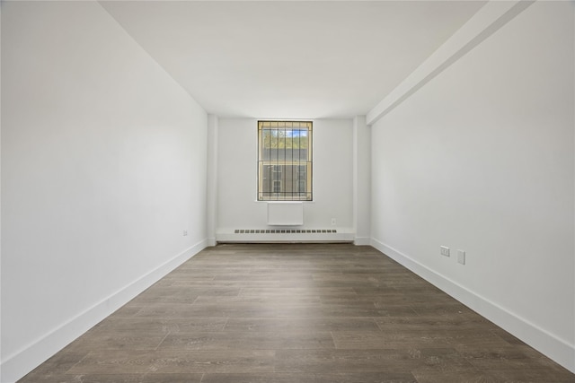 unfurnished room with dark wood-style flooring, baseboards, and a baseboard heating unit