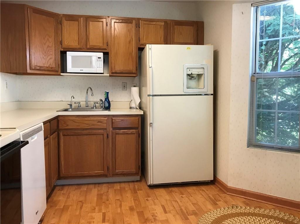 179 Hidden Ridge Dr, Monticello, NY 12701 - kitchen featuring white appliances, a sink, light wood-style flooring, and brown cabinets