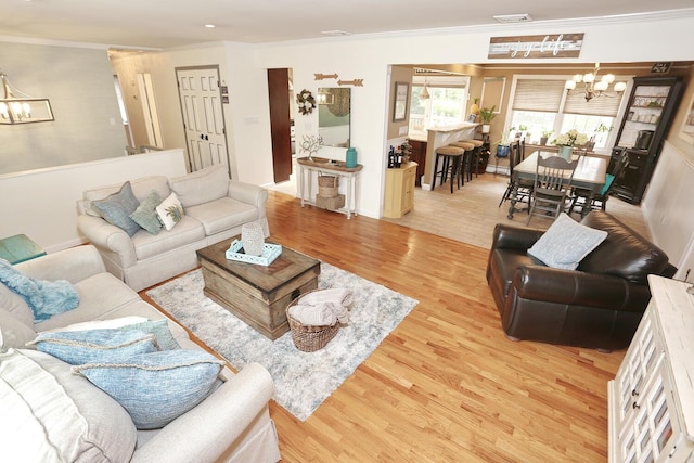 living area featuring a chandelier, ornamental molding, wood finished floors, and a baseboard heating unit