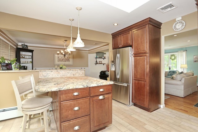 kitchen featuring stainless steel fridge with ice dispenser, light wood finished floors, ornamental molding, a breakfast bar area, and pendant lighting