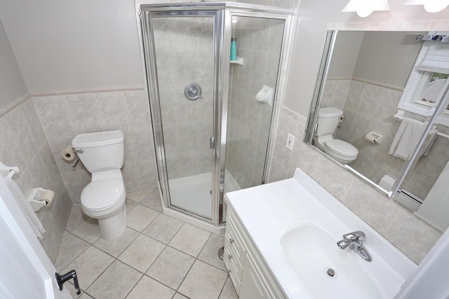 bathroom featuring tile walls, toilet, tile patterned flooring, a stall shower, and wainscoting
