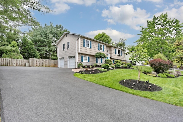 raised ranch featuring a garage and asphalt driveway