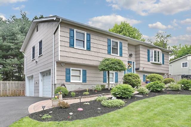 raised ranch featuring a garage and asphalt driveway