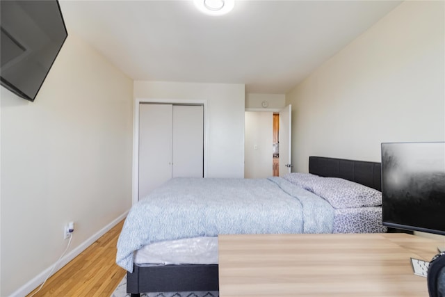 bedroom with wood finished floors, a closet, and baseboards