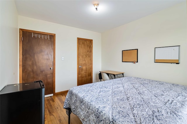 bedroom featuring light wood finished floors, two closets, and baseboards
