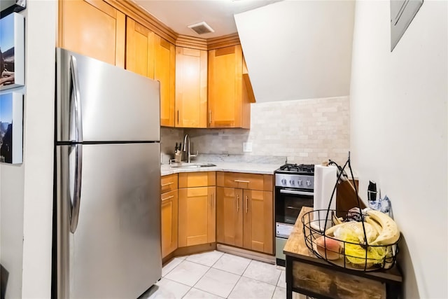 kitchen featuring appliances with stainless steel finishes, a sink, tasteful backsplash, and light tile patterned floors