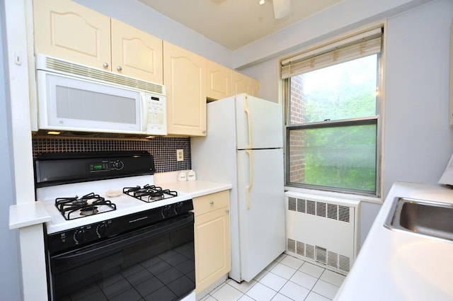 kitchen featuring white appliances, radiator, backsplash, light countertops, and a sink