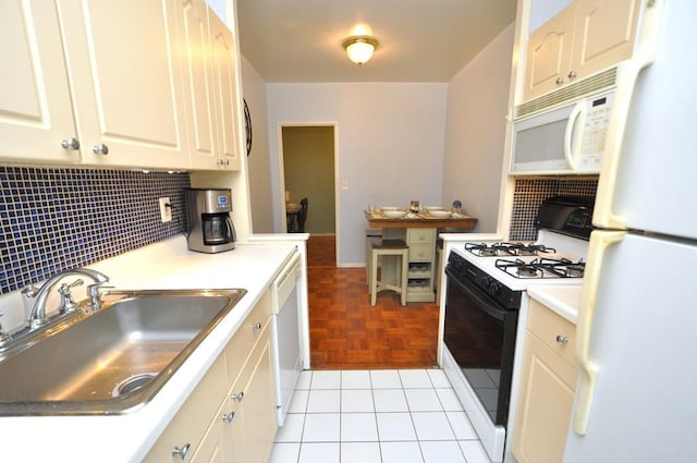 kitchen with white appliances, a sink, light countertops, tasteful backsplash, and white cabinetry