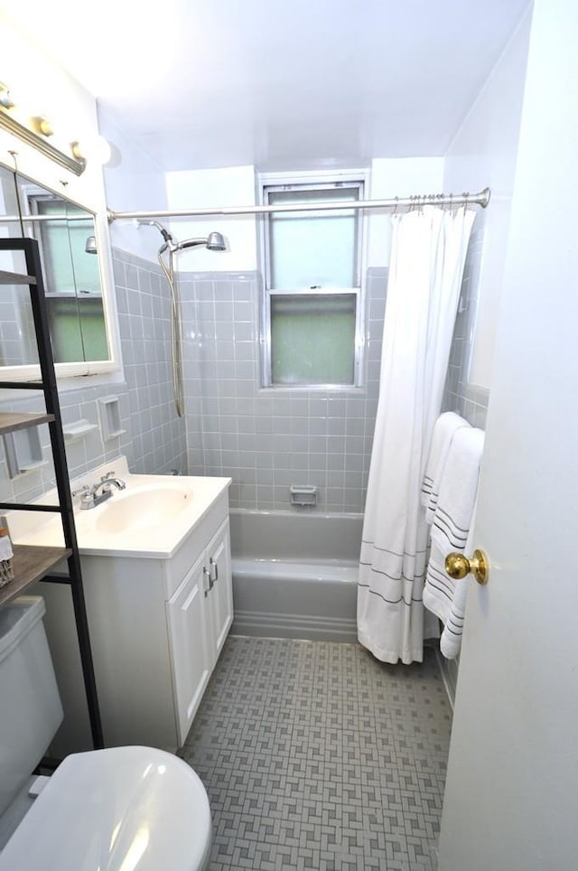 bathroom featuring shower / bath combination with curtain, vanity, tile patterned floors, toilet, and tile walls