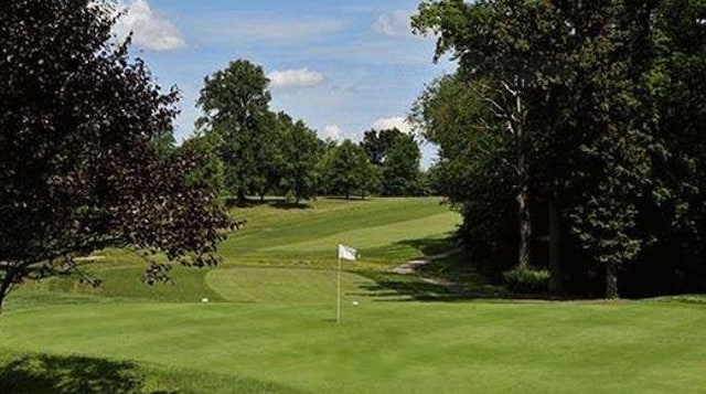 view of property's community featuring golf course view, a putting area, and a lawn