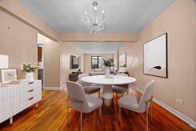 dining space with a chandelier, baseboards, and wood finished floors