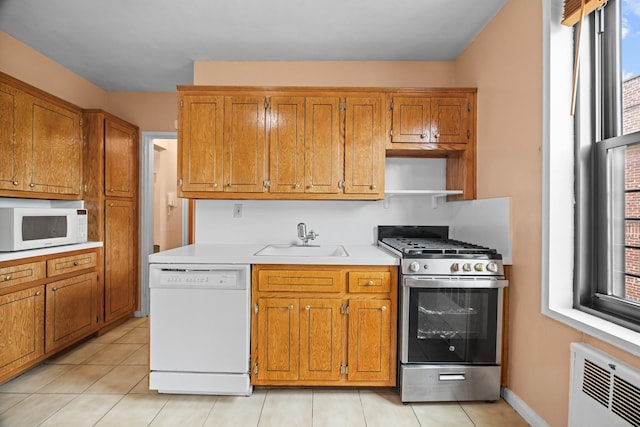 kitchen featuring white appliances, a sink, light countertops, brown cabinetry, and light tile patterned flooring