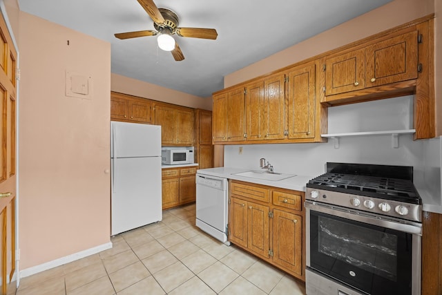 kitchen featuring white appliances, a sink, light countertops, brown cabinetry, and ceiling fan