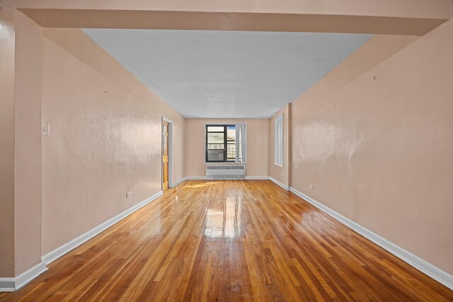spare room featuring hardwood / wood-style floors, baseboards, and radiator