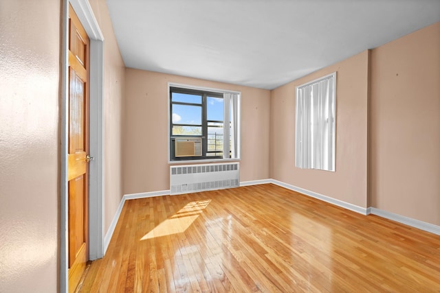 spare room with radiator heating unit, hardwood / wood-style flooring, and baseboards
