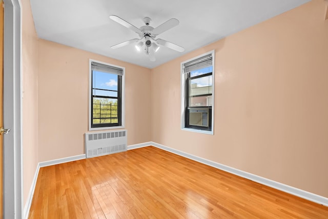 empty room with radiator, light wood-style floors, baseboards, and a ceiling fan