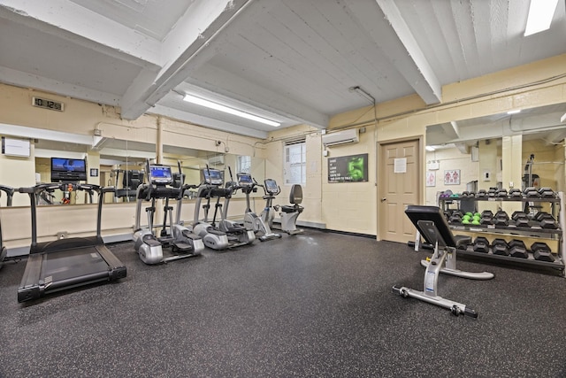 workout area featuring a wall mounted AC and beam ceiling