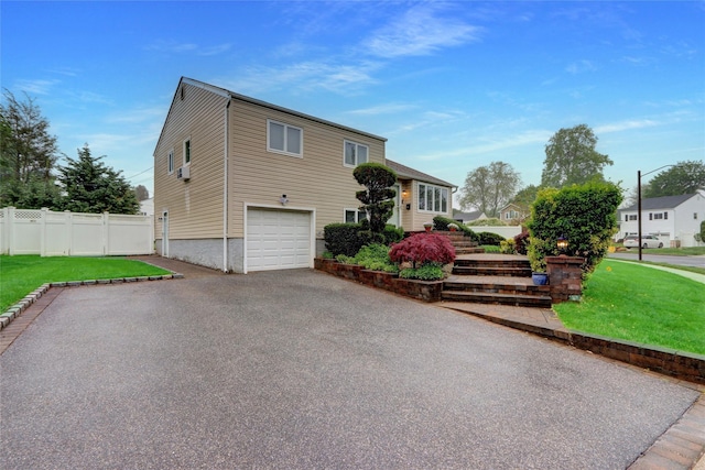 tri-level home with a garage, fence, a front yard, driveway, and stairs