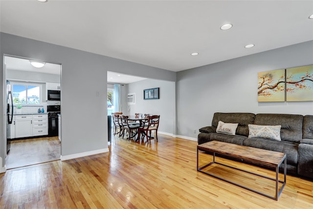 living room with baseboards, light wood-style flooring, and recessed lighting