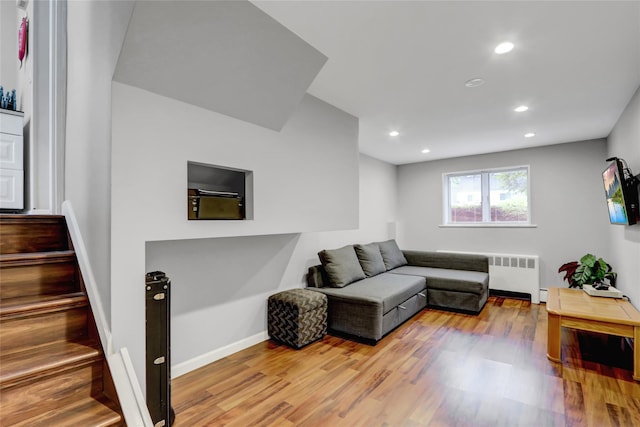 living area featuring wood finished floors, radiator, recessed lighting, baseboards, and stairs