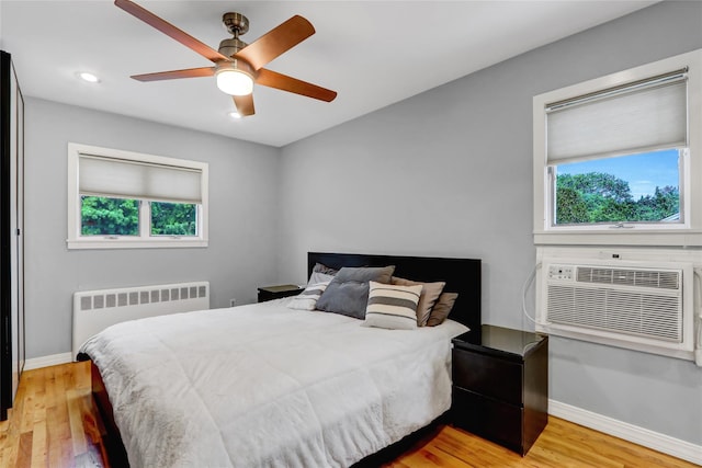 bedroom featuring light wood-style floors, recessed lighting, baseboards, and radiator heating unit
